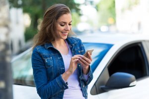 Woman sitting in front of car on cell phone